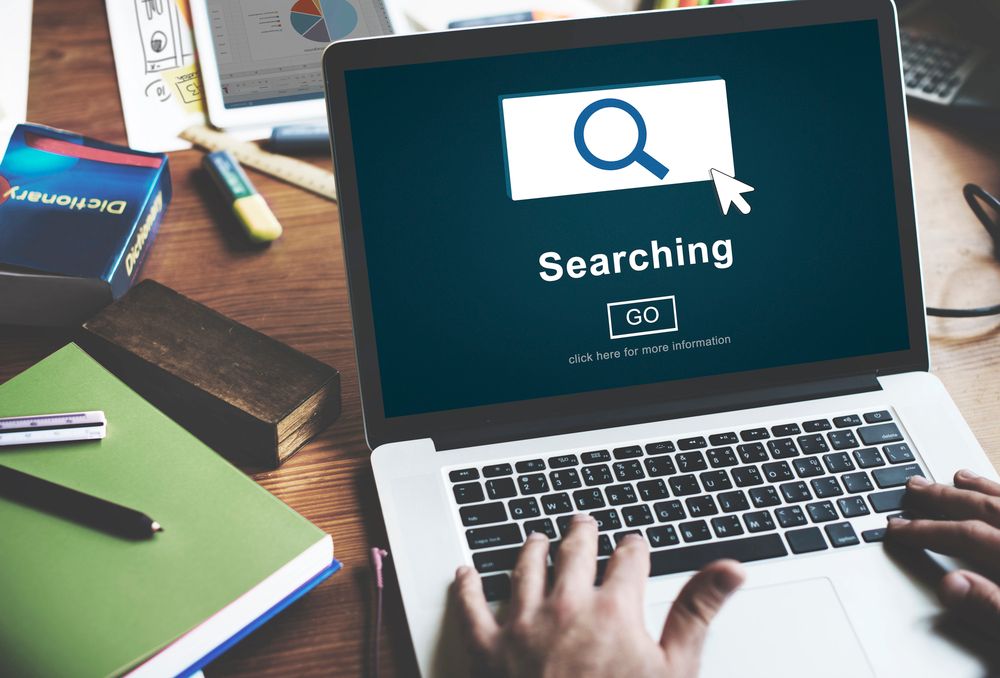 Person using a laptop with a search engine page open, showing a search bar, magnifying glass icon, and the word “Searching” above a “GO” button—highlighting AI search optimization for mediators seeking efficient solutions.